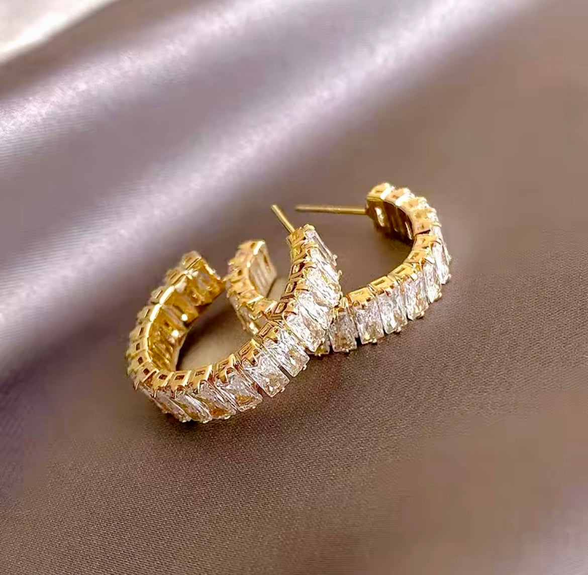 Pendientes en tono dorado con un diseño único similar a un trébol, que le da un giro juguetón al estilo clásico de aro. Perfectos para cualquier ocasión.